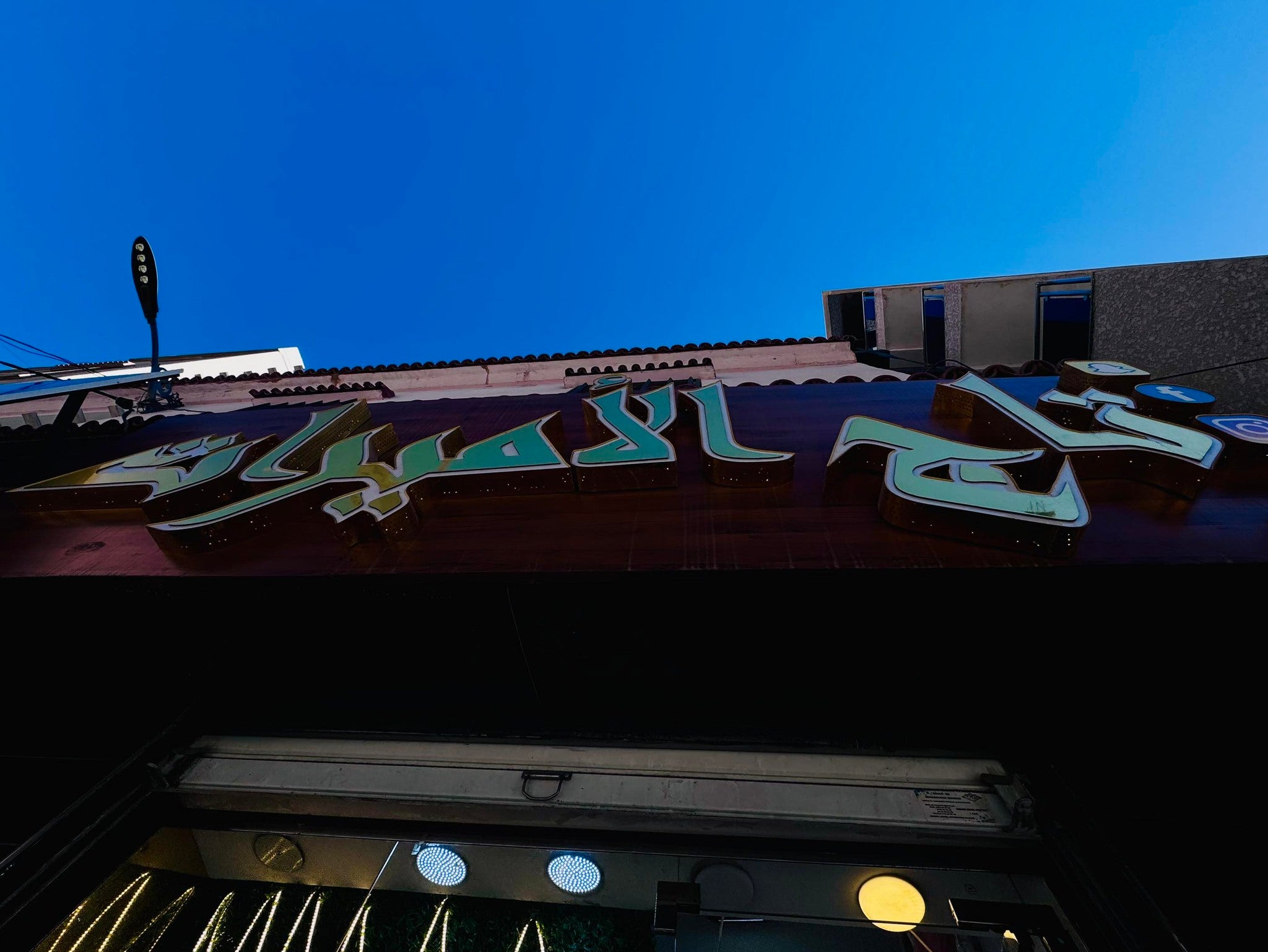 Neon sign on a building with a clear blue sky above